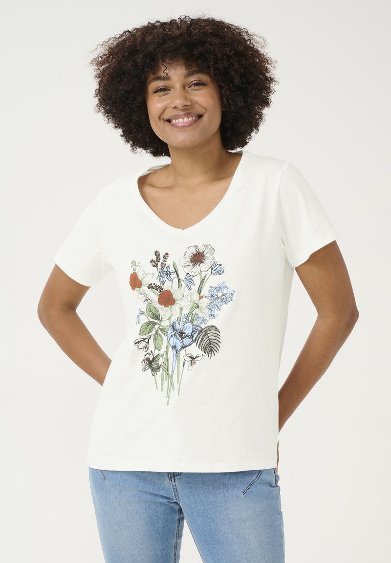 T-shirt en coton blanc avec un col en V, présentant un design floral en bleu, rouge et vert. Manches courtes et coupe décontractée.