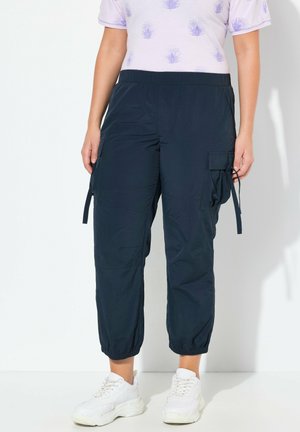 Pantaloni cargo blu navy con polsini elasticizzati, tasche laterali e cordoncino regolabile. Abbinato a una maglietta a maniche corte lilla.