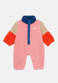 Fleece-Einteiler in Pink mit blauer Kragen und Knöpfen. Hat orangefarbene und beige strukturierte Ärmel. Auffälliges "TINY"-Label auf der Vorderseite.