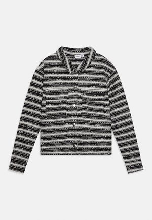 Giacca a righe bianche e nere a maniche lunghe con bottoni, colletto e tasca frontale, distesa su sfondo bianco.