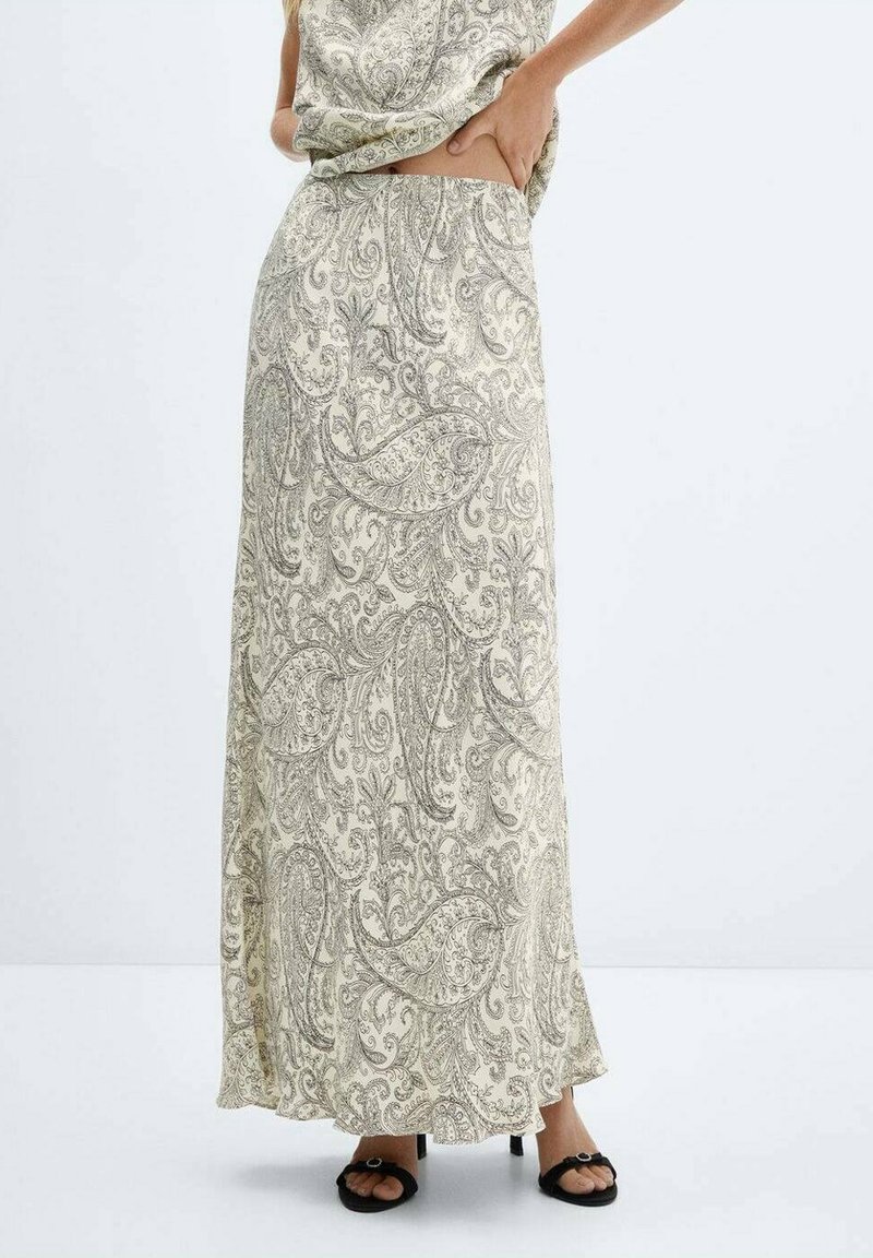 Maxinederdel i lyst beige stof med indviklede sorte paisley-mønstre. Materialet virker blødt med en flydende silhuet og en sideslids.