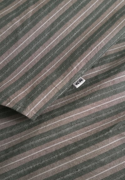 Tekstiili, jossa on vuorottelevat vihreät ja beige raidat sekä teksturoitu pinta. Kankaassa näkyy pieni valkoinen tunniste, jossa lukee "W.W.W.".