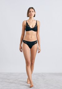 Melns mežģīņu apakšveļas komplekts ar braletīti ar regulējamām siksnām un atbilstošām biksītēm. Mīksts audums un smalkas mežģīņu detaļas.