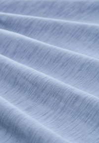 Tela texturizada de color azul claro con sutiles líneas diagonales, que exhibe una superficie suave y lisa y se drapea suavemente en ondas.