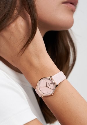 Pink leather strap watch featuring a round, rose gold case, a pink face with minimalistic hour markers, and a textured strap.