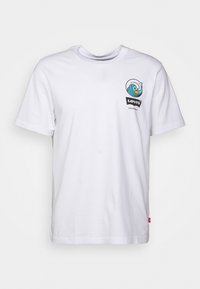 T-shirt en coton blanc avec un graphique de vagues colorées et le texte "Levi's California", manches courtes, et une petite étiquette rouge sur le côté.