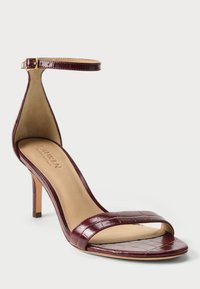 Μπορντό σανδάλι με ψηλό τακούνι, με γυαλιστερό σχέδιο κροκόδειλου, ιμάντα στον αστράγαλο, ανοιχτή μύτη και μπεζ επένδυση εσωτερικά. Διαθέτει λεπτό τακούνι στιλέτο.