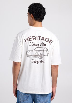 T-shirt blanc en coton à manches courtes, avec le texte marron « HERITAGE Racing Club » et un dessin au trait d'une voiture dans le dos.