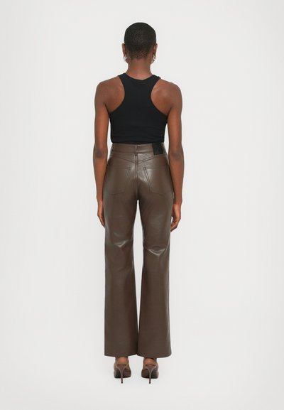 Brown leather flared pants with a smooth texture, featuring back pockets and a black label at the waistband, styled with a black tank top.