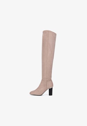 Wysoki beżowy zamszowy kozak sięgający do kolana, z blokowym obcasem i spiczastym noskiem, widziany z boku na białym tle.