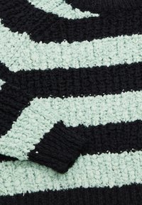 Tessuto a strisce nero e verde menta con un design tessuto testurizzato. Le strisce alternano in larghezza, mostrando una texture morbida e ad anello.