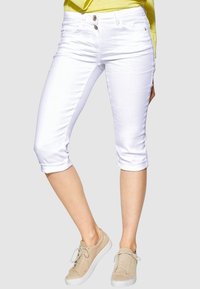 Witte cropped jeans met een Gladde textuur, twee knopen, en opgerolde boorden, gecombineerd met lichtbeige sneakers.