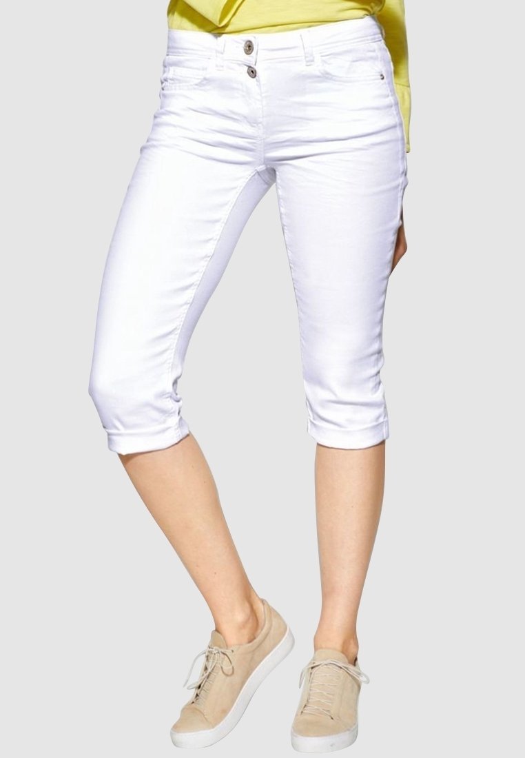 Witte cropped jeans met een Gladde textuur, twee knopen, en opgerolde boorden, gecombineerd met lichtbeige sneakers.