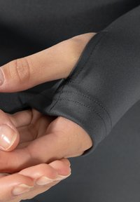 Sort langærmet top med en tætsiddende design. Har et glat, strækbart stof og tommelfingerhuller ved manchetterne for bedre dækning.