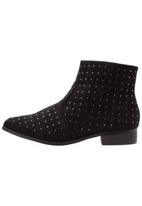Botines de ante negro con punta afilada, adornados con tachuelas plateadas y un tacón bajo cuadrado para mayor estabilidad. Textura suave en todo.