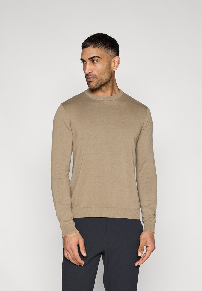 Μπεζ πλεκτό πουλόβερ με στρογγυλή λαιμόκοψη, μακριά μανίκια και ριμπ μανσέτες και τελείωμα. Ομαλή υφή και εφαρμοστή γραμμή.