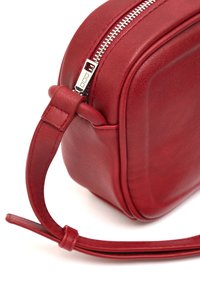 Borsa a tracolla rossa in pelle con una texture liscia, forma arrotondata e zip argentata. Include una spalla sottile e regolabile.