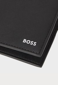 Black textured wallet made of synthetic material, featuring a prominent white "BOSS" logo and contrasting stitching along the edges.