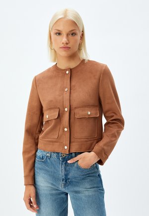Bruine suède cropped jas met een ronde hals, sluiting met knopen aan de voorkant en twee zakken aan de voorkant. Kenmerkt zich door een gladde textuur en minimale details.