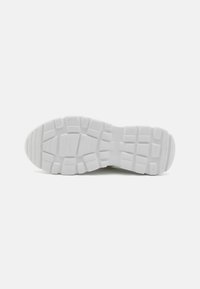 Semelle de sneaker blanche avec une surface en caoutchouc texturée comportant des rainures et des sections surélevées pour l'adhérence. Bout arrondi et large zone de talon.