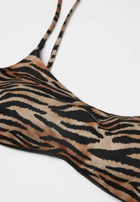Bikini top s tygřím vzorem a tenkými ramínky. Tkanina má hladký povrch s odstíny černé a oranžové v odvášném vzoru.