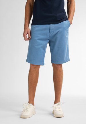 Lichtblauwe katoenen shorts met een rechte voorkant en twee zijzakken, met een eenvoudig ontwerp en een lichte glans. Gecombineerd met witte sneakers.