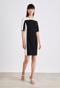 Schwarz-weißes, farbblockiertes Kleid mit kurzen Ärmeln, rundem Ausschnitt und figurbetonter Silhouette. Glattes Material mit einem klaren, modernen Design.