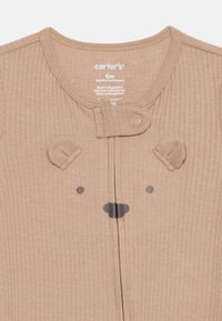 Tan ribbed onesie with bear face design, featuring embroidered ears, nose, and eyes. Includes a zipper and snap closure for easy dressing.