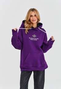 Fialová mikina s kapucí z bavlněné směsi. Obsahuje přední kapsu, stahovací šňůrku a vyšitý motiv můry s textem. Pohodlný střih.