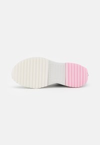 Semelle d'une basket avec une surface blanche texturée qui passe à un accent rose ; présente des motifs nervurés pour l'adhérence et le branding.
