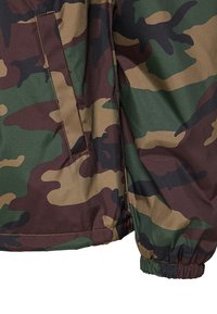 Manche et poche de veste à motif camouflage avec poignet élastique et couture visible dans des tons de vert, marron et noir.