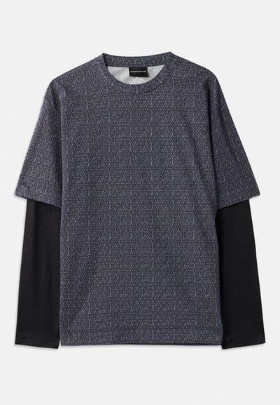 Camisa de manga curta com um padrão geométrico em azul e preto. Apresenta uma camada de manga longa preta por baixo, gola redonda e uma textura de tecido suave.