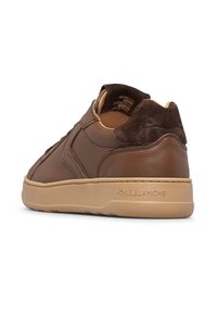 Sneaker in pelle marrone con finitura liscia e accenti in suede. Presenta una suola in gomma beige e un dettaglio con il marchio sul tallone. Design a taglio basso.