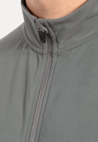 Grå zip-up jakke med høj krave, glat tekstur og kontrastlynlås. 