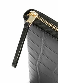 Czarna, fakturowana skórzana saszetka z rogiem, złotym zamkiem błyskawicznym i uchwytem, prezentująca szczegółowe przeszycia oraz wytłoczoną nazwę marki na uchwycie zamka.