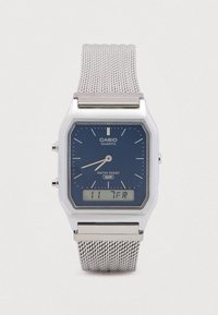 Orologio Casio al quarzo con quadrante blu, cinturino a maglia d'argento, cassa quadrata in plastica, display digitale e funzione di resistenza all'acqua.