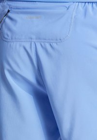 Jasnoniebieskie szorty sportowe wykonane z oddychającego materiału, charakteryzujące się gładką fakturą i małą kieszonką na zamek z tyłu.