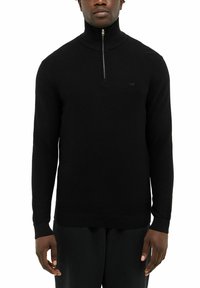 Schwarzer gestrickter Pullover mit hohem Kragen, halbem Reißverschluss und langen Ärmeln. Mit einem subtilen Logo auf der Brust sowie gerippten Bündchen und Saum.