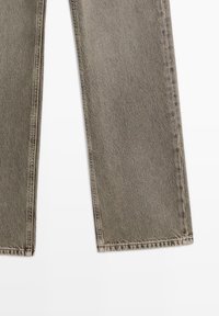 Jeans a gamba larga grigio scuro con una texture leggermente sbiadita, dotati di cuciture standard e un taglio dritto al fondo.