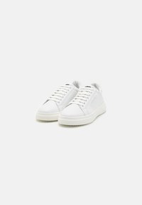 Witte leren sneakers met een ronde neus, platte rubberen zool en vetersluiting aan de voorkant. Kenmerken zijn een verhoogd logo aan de zijkant en een textiel stof op de tong.