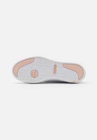 White sneaker sole with a herringbone pattern, featuring pink textured heel and toe pads and a small circular grip near the ball of the foot.
