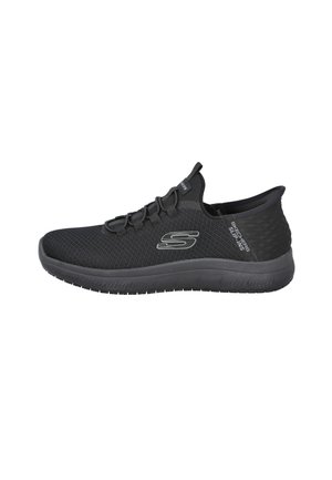 Zapatilla deportiva negra Skechers sin cordones con parte superior de malla, cordones elásticos y suela gruesa de goma mostrada desde el lado exterior.