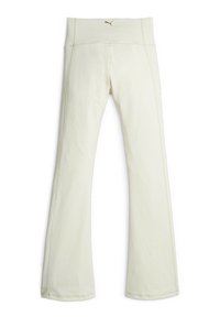 Leggings évasés crème avec une taille haute, fabriqués en tissu doux, arborant un accent en logo doré près de la taille et des détails de couture soignés.