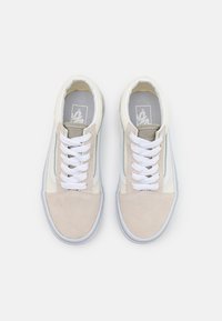 Zapatillas beige claro con materiales de ante y lona, cordones blancos, acentos grises y un diseño minimalista. Suelas de goma y lengüeta acolchada.