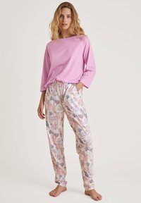 Lichtroze langemouwen top gecombineerd met patroon gedrukt, bloemenpyjama broek van zachte stof. Touwsluiting taille, ontspannen pasvorm, casual ontwerp.
