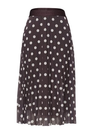 Henkilön vyötärö ja kädet, joka pukeutunut mustaan plissoonihameeseen, jossa on valkoisia pilkkuja, ja siihen sopivaan mustaan yläosaan.