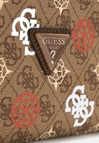 Brązowa torba z teksturowanej tkaniny z białymi i czerwonymi akcentami logo, trójkątną plakietką z logo oraz misternymi wzorami.