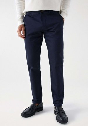 Pantalones azul marino de corte slim, confeccionados en tela suave, con cierre frontal de botón, bolsillos laterales y diseño de frente plano.