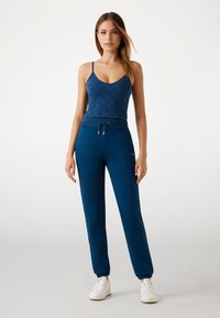 Top in blu navy con un motivo discreto e spalline sottili, abbinato a pantaloni jogger coordinati con caviglie a coste e vita regolabile con cordino.