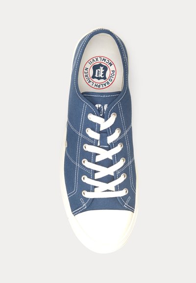 Marinblå canvas sneakers med vit gummisula och snören. Har sömnadsdetaljer och logotyp på innersulan. Rundad tådesign.